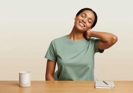 Smiling black woman stretching her neck and shoulder while sitting comfortably at a desk, taking a relaxing break from work. concept of wellness, stress relief, and office ergonomics.の素材