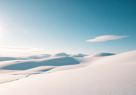 Vast pristine winter landscape featuring smooth, rolling snow covered hills and gentle peaks under a bright, clear blue sky. cold, serene, and expansive nature scene.の素材