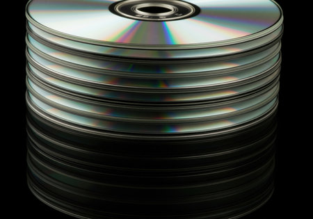 Stack of shiny silver optical media discs piled vertically, reflecting colorful light. represents data storage, technology, and digital archives.の素材