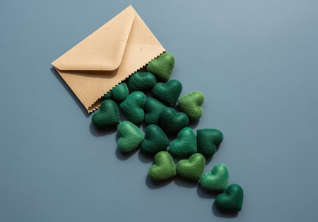 An open kraft paper envelope releases many small, textured green hearts, creating a visual metaphor for delivering love, care, or eco friendly messages.の素材