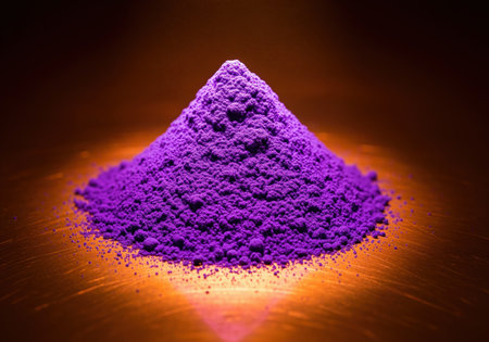 Conical pile of vibrant purple powder, possibly pigment or spice, dramatically lit against a warm, reflective copper surface. abstract texture and contrasting colors create visual impact.の素材