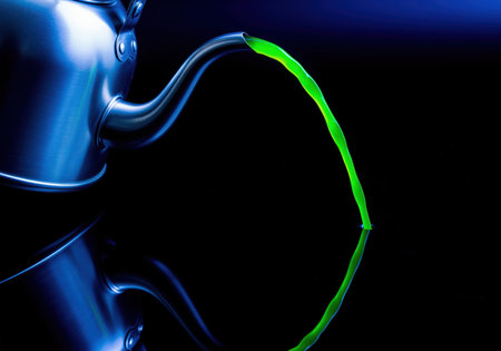 Sleek metallic kettle illuminated by blue light pouring a vibrant stream of neon green liquid onto a reflective black surface. high contrast, abstract concept of flow, chemistry, or toxic substance.の素材