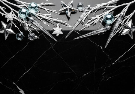 Elegant winter border composed of silver ornaments, metallic stars, clear icicles, and frosted white branches set against a luxurious black marble surface with copy space.の素材