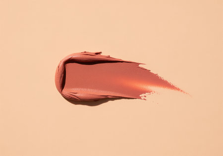 Textured matte nude terracotta lipstick or lip gloss swatch applied to a smooth pale peach surface. ideal for beauty, cosmetic, and makeup advertising concepts.の素材