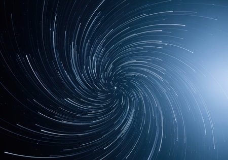 Dynamic blue and silver star trails captured using long exposure astrophotography, forming a mesmerizing spiral vortex pattern in the deep night sky, symbolizing time, rotation, and cosmic energy.の素材