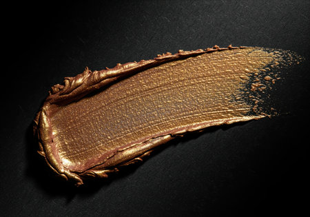 A close up view of a thick, luxurious stroke of shimmering metallic gold cosmetic product, possibly eyeshadow or highlighter. this swatch showcases rich texture and iridescent shine, perfect for beauty and luxury themes.の素材