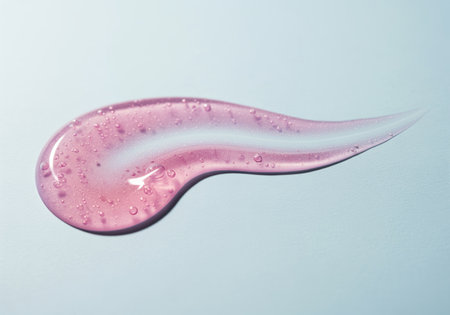 Pink cosmetic serum gel texture swatch with air bubbles spread in an elegant streak on a light surface. focus on beauty, hydration, and skincare concept.の素材
