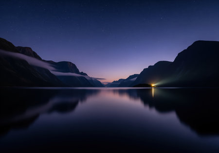 Tranquil fjord reflecting dark mountain silhouettes under a deep indigo night sky with stars. a bright light source casts a dramatic beam across the still water.の素材
