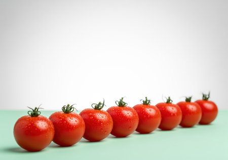 Pristine, bright red cherry tomatoes arranged in a horizontal line, covered in fresh water droplets. studio shot on a light aqua surface with ample white copy space above. focus on freshness, ingredient, and healthy food concepts.の素材