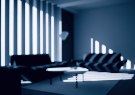 Blurred photographic texture of a minimalist scandinavian style loft interior, featuring a sofa and table, bathed in dramatic vertical stripes of light and deep navy blue shadows.の素材