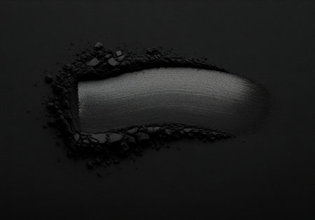 Black cosmetic powder with a velvety matte texture. the powder is subtly disturbed by a single, elegant sweep, creating a smooth and refined appearance on dark surface.の素材
