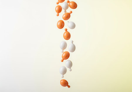 Orange and white beauty serum gel capsules falling vertically against a soft, bright gradient background. concept of skincare, health, and wellness.の素材
