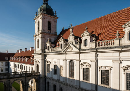 Grand baroque monastery complex featuring a detailed white facade, prominent bell tower, and expansive red tiled roof under a bright blue sky. historic european architecture.の素材