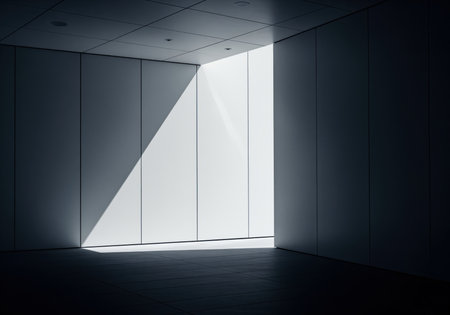 Modern abstract architectural space featuring dark walls and floor, dramatically illuminated by a strong, bright diagonal shaft of light entering through a narrow opening. emphasizes contrast, geometry, and minimalism.の素材