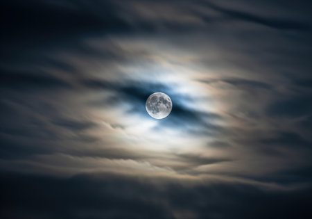 Full moon shining brightly through a veil of dark, fast moving storm clouds. the scene evokes mystery, drama, and celestial power in the deep night sky.の素材