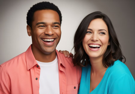 Multiracial couple, a black man and a caucasian woman, laughing brightly together in a studio portrait. expressing joy, connection, and authentic happiness.の素材