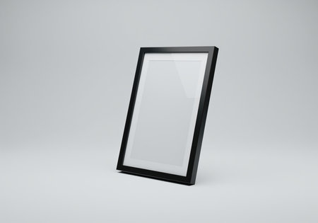Black vertical picture frame with a white mat, leaning slightly on a neutral gray studio surface. ideal for art, photo, or poster mockups and presentations.の素材