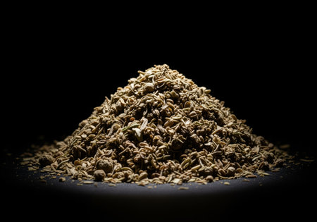 Pile of dried marjoram spice and herbs dramatically lit against a dark, black background. essential ingredient for cooking, seasoning, and enhancing food flavor. used in mediterranean and european cuisine.の素材