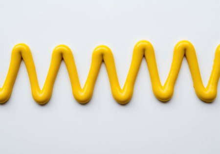Thick, bright yellow mustard condiment squeezed onto a white surface, forming a continuous, uniform zig zag or wavy pattern. ideal for food design, flavor, and graphic backgrounds.の素材