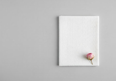 White textured fabric swatch displayed in a minimalist flat lay composition. a delicate pink rosebud rests on the corner against a neutral gray background. ideal for textile, beauty, or wedding concepts.の素材