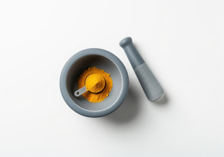Modern gray ceramic mortar and pestle set filled with vibrant yellow spice powder and a measuring spoon, shot from above. ideal for cooking or wellness concepts.の素材