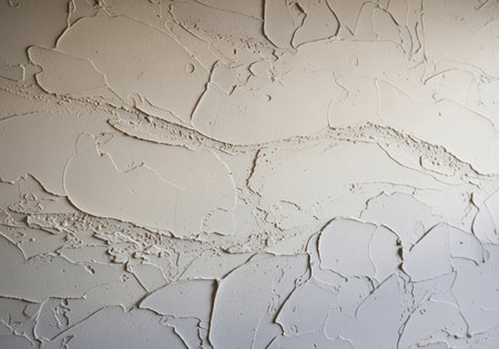 Textured off white plaster wall surface featuring thick, rough stucco finish and abstract, handcrafted relief pattern. ideal for background or architectural detail.の素材