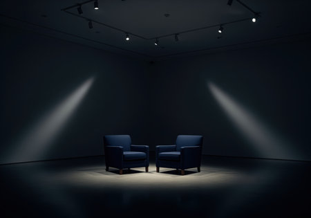 Two deep midnight blue armchairs centered under dramatic spotlights in a vast, empty, low key interior space. setting suggests an interview, conversation, or isolated exhibition.の素材