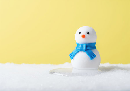 Miniature snowman figure wearing a blue scarf is melting into a puddle on white snow. conceptual image representing climate change, global warming, and temperature rise.の素材