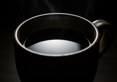 Steaming cup of dark filter coffee with a reflective surface, presented in a low key cinematic style. evokes warmth, morning ritual, energy, and comfort.の素材