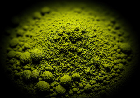 Finely powdered vibrant green substance, possibly matcha or algae, in a detailed macro shot. granular texture and small clumps visible, creating a visually striking abstract pattern.の素材