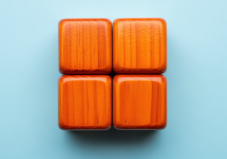 Four identical, brightly varnished wooden blocks with visible grain, arranged in a grid on a clean light blue background. minimalist design for concepts like structure, organization, and simplicity.の素材
