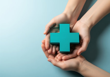 Two cupped hands tenderly hold a vibrant teal cross, symbolizing health, medical support, and compassionate care. this image is ideal for themes of wellness, charity, and healthcare services.の素材