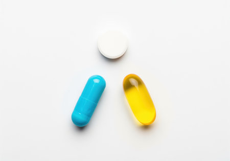 A clean flat lay composition featuring a white round tablet, a blue elongated capsule, and a yellow oval softgel. these pills represent various forms of medication and dietary supplements.の素材