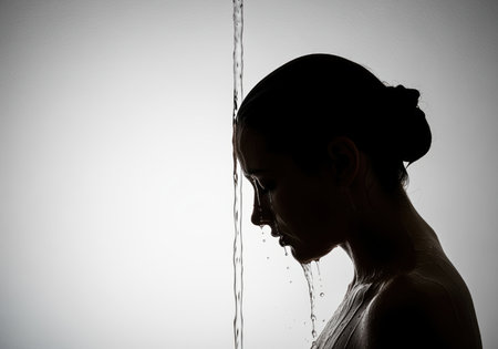 A striking side profile of a woman silhouette as a stream of water cascades over her head and face, creating a dramatic and contemplative mood. ideal for themes of purity, cleansing, or emotional release.の素材