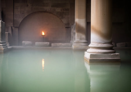 Ancient, atmospheric water pool surrounded by massive stone columns and walls, illuminated by a glowing torch. Steam rises from the surface, creating a mystical and tranquil scene.の素材