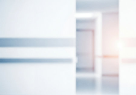 Abstract blurred background featuring a clean, bright, modern interior corridor with white walls, reflective floor, and a warm light flare. Ideal for medical, corporate, or technology-related visual compositions.の素材