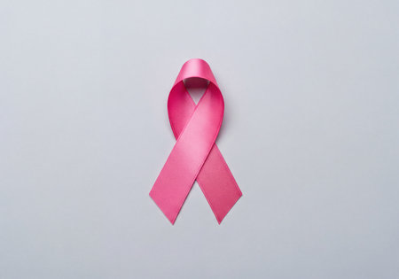 Pink ribbon positioned centrally on a light gray background. This powerful symbol represents breast cancer awareness, support, health care, and the ongoing global campaign for prevention, early detection, and a cure.の素材