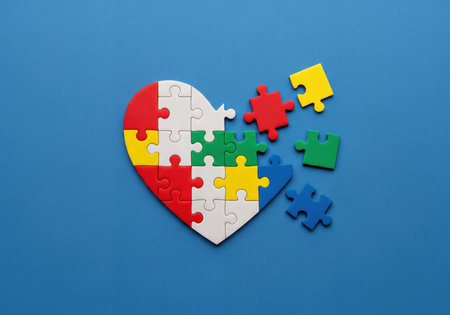 A heart-shaped puzzle, made of colorful pieces against a vibrant blue backdrop, represents autism awareness, community support, and the journey of connection and understanding.の素材
