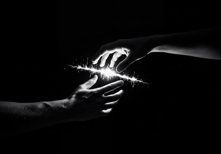 Dynamic luminous energy spark connecting two outstretched human hands in a black and white composition. Concept of communication, power, and connection on a dark background.の素材