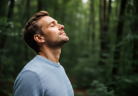 Calm man with eyes closed in profile, breathing fresh air and experiencing peace amidst a tranquil green forest, embracing nature&#39;s serenity.の素材