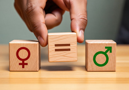 Hand placing wooden block with equals sign between female and male gender symbols, illustrating concept of equality, equity, human rights, and social justice for all genders.の素材