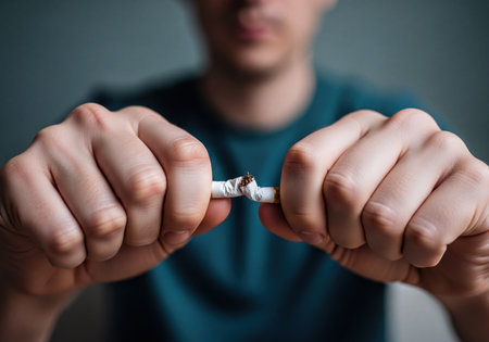 Man&#39;s hands forcefully breaking a cigarette in half, symbolizing the strong decision to quit smoking and overcome addiction. Represents a commitment to a healthier, smoke-free lifestyle and self-control.の素材
