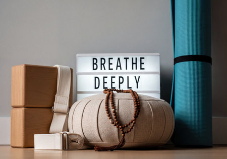 Essential yoga and meditation equipment including wooden blocks, strap, Zafu cushion, mala beads, and a light box displaying 'Breathe Deeply' for mindfulness practice.の素材