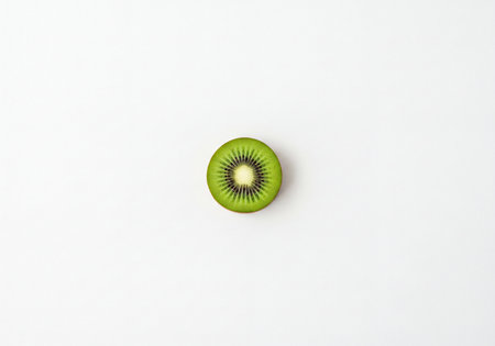 Juicy kiwi half, precisely cut, revealing bright green flesh and black seeds against a pristine white surface. Represents healthy snack, diet and natural vitamin source.の素材