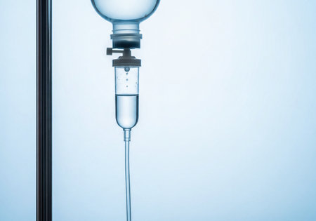 Close-up of a medical intravenous fluid device, with clear liquid dripping into a transparent chamber. Essential equipment for patient hydration, medication delivery, and medical treatment in a healthcare environment. Sterile conditions and fluid movement are visible.の素材