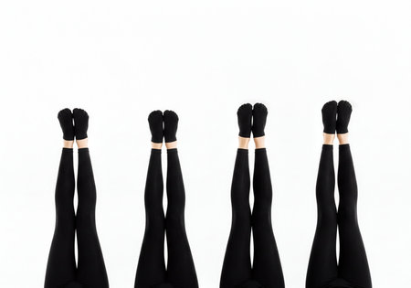 Four pairs of human legs clad in black leggings and socks are arranged vertically, feet pointing skyward. this abstract composition suggests unity, exercise, or relaxation.の素材