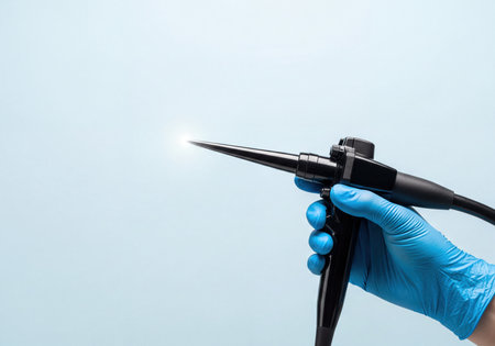 Gloved hand of a medical professional holds an endoscope with a glowing, bright tip, ready for internal examination or diagnostic procedure. Focus on medical technology, endoscopy, and healthcare.の素材