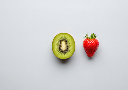 Green halved kiwi fruit with visible black seeds next to a vibrant red strawberry with a green stem, arranged neatly on a clean white background, symbolizing fresh, healthy food and natural ingredients.の素材