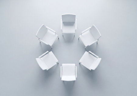Six modern white chairs forming a perfect circle on a subtle gray floor, viewed from above. Represents team meeting, collaboration, group discussion, or seating arrangement in a therapy session.の素材