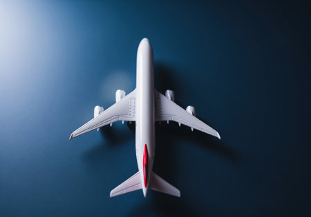A top down aerial view of a white passenger airplane model on a clean dark blue background representing concepts of air travel, tourism, transportation, and the aviation industry.の素材